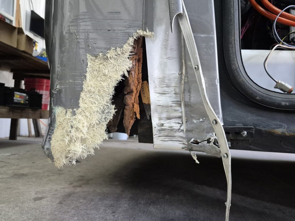 RV cargo bay door torn open, before repair RV cargo bay door torn open, fiberglass skin and substrate exposed, before collision repair